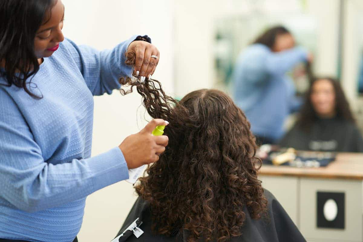 hair stylist spraying product onto clients hair