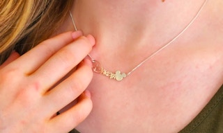 someone wearing a personalized necklace with the name emily in a disney font