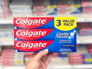 hand holding a 3 pack of colgate cavity protection toothpaste at target