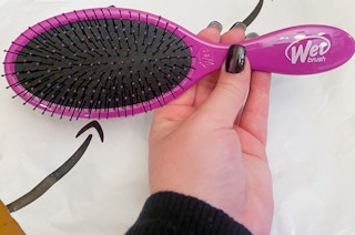 hand holding a wet brush over an amazon package