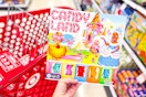 person holding a candy land board game over a target shopping cart