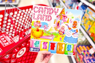 person holding a candy land board game over a target shopping cart