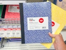 hand holding 2 dealworthy composition notebooks in front of target shelf