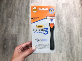 hand holidng bic razor package over the top of wood floor