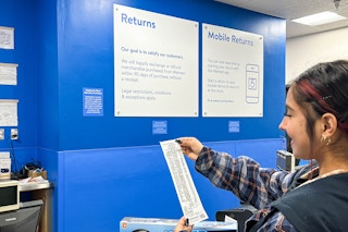 a person holding a receipt at the walmart return area 