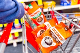 person placing bags of dunkin coffee in a cart