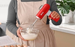 a person using a red hand mixer in a bowl
