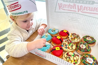 a child looking at a box of Elf donuts from Krispy Kreme