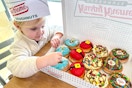 a child looking at a box of Elf donuts from Krispy Kreme