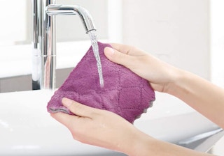 a person holding a purple cloth under running water