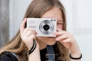 person holding a white digital camera