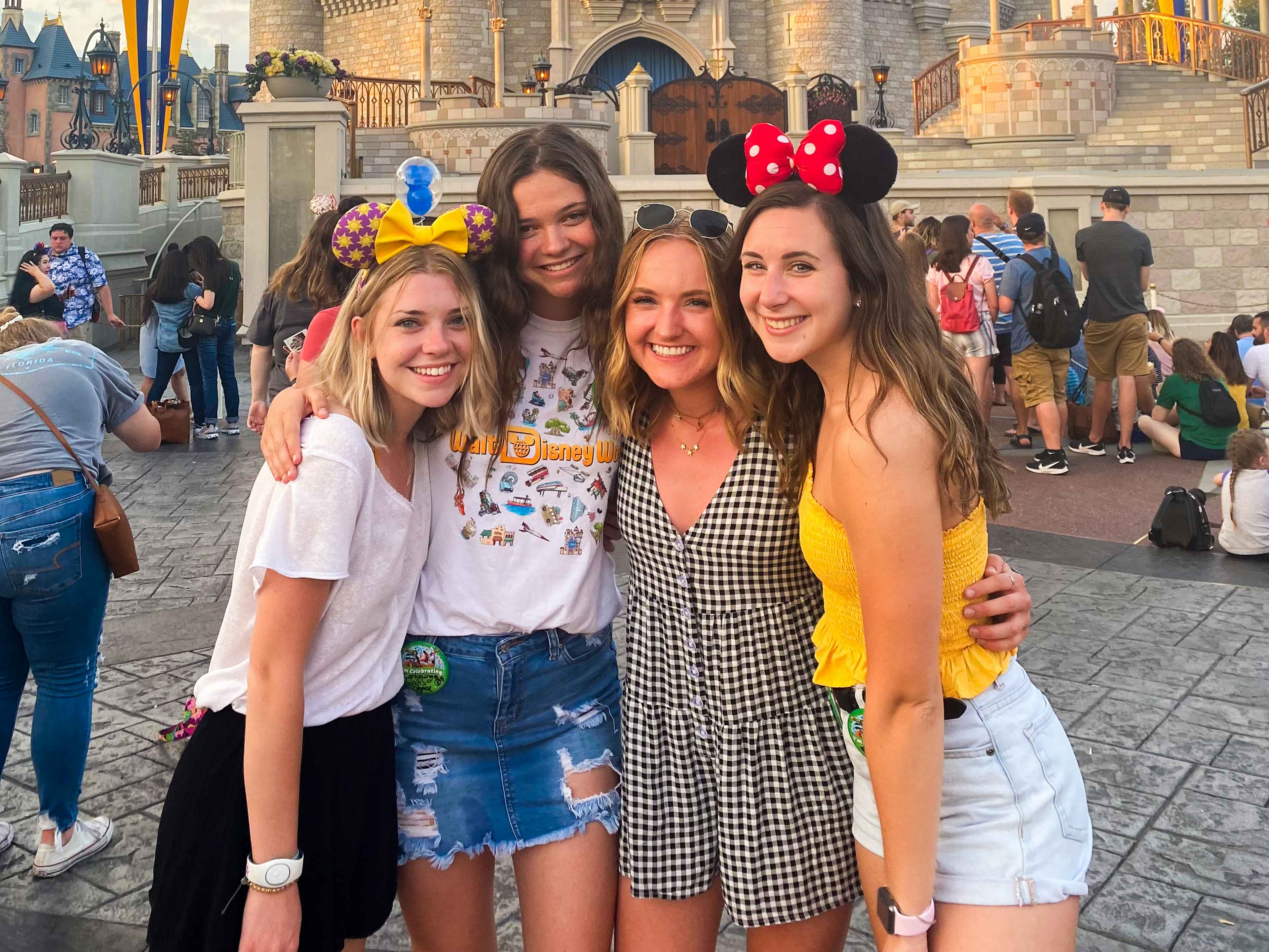 four friends hugging each other in front of the magic kingdom castle at disney world