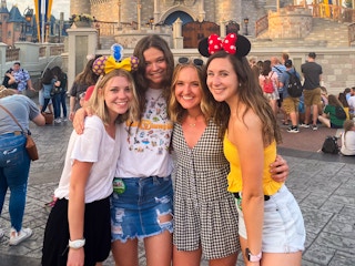 four friends hugging each other in front of the magic kingdom castle at disney world