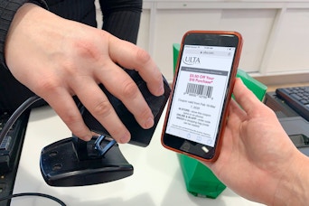 An ulta employee scanning a mobile coupon at checkout.