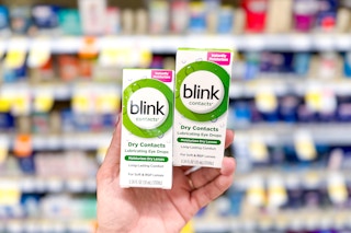 hand holding two boxes of eye drops in front of store shelves