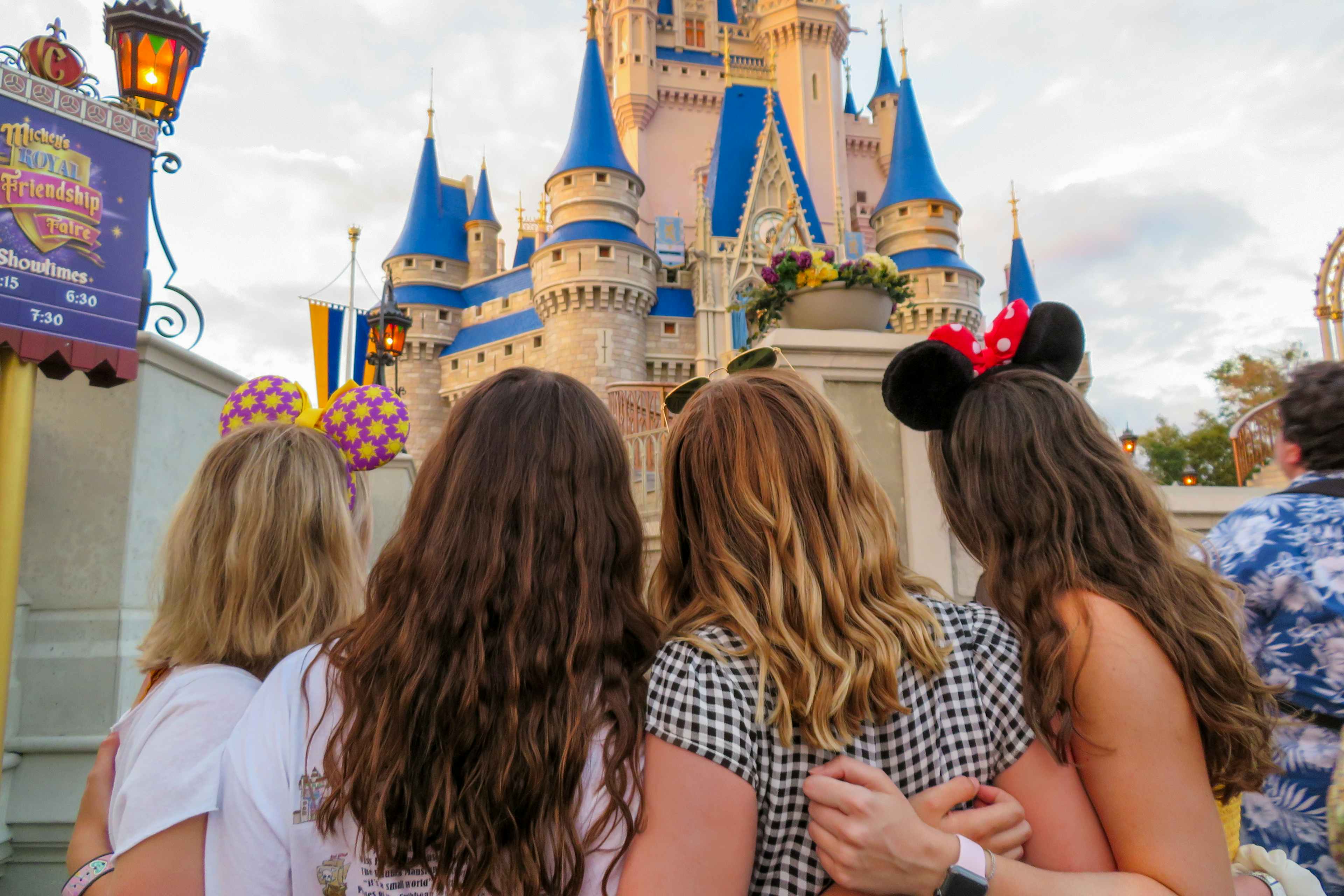 four friends hugging each other in front of the magic kingdom castle at disney world