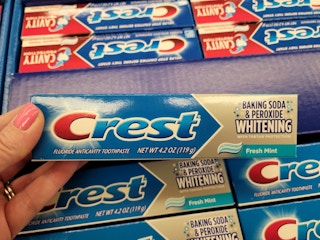hand holding a tube of crest toothpaste at kroger