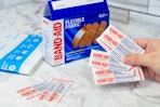 a box of Band-Aids next to a hand holding bandages