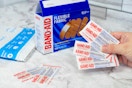 a box of Band-Aids next to a hand holding bandages