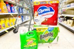 gain detergent, bounty paper towels, and charmin toilet paper in an aisle in front of a cart