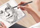 a person drawing on an iPad with a stylus pen