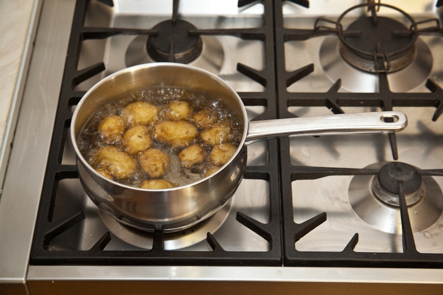 A pot of potatoes boiling on a stove.