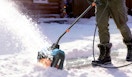 a person using a electric snow shovel in snow