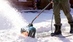 a person using a electric snow shovel in snow
