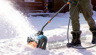 a person using a electric snow shovel in snow