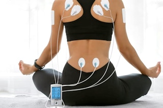 woman meditating while using muscle stimulator