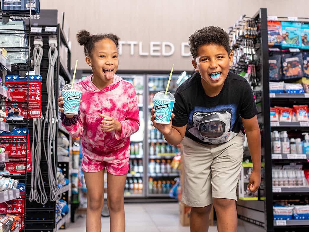 two happy kids in 7-eleven holding slurpees