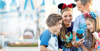 family at disney park looking at phone