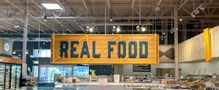 sign hanging from the ceiling at whole foods reads real food