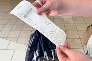 Someone holding up a receipt for a GAP purchase with a GAP bag