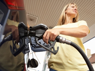 A person inserting a gas pump nozzle into their car to fill the tank.