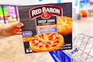 hand holding red baron pizzas on shopping cart