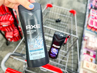 person holding axe body wash over a cart with another bottle of body wash in it