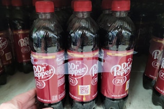 hand touching dr pepper soda 6-pack sitting on shelf at dollar general