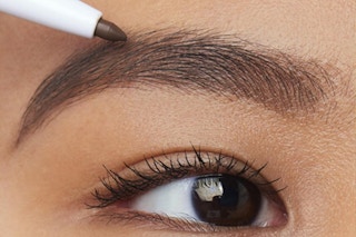 a woman applying a brow pencil on her eyebrow