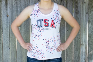 A person wearing a white Old Navy USA tank top with stars stenciled on in red and blue.