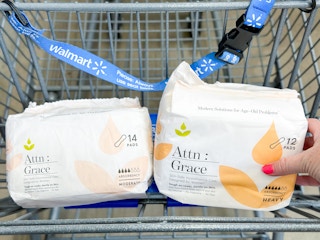 a hand holding a 12-count of pads while a 14-count sits in a Walmart cart