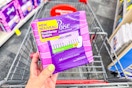 person holding a pack of poise pads over a cart
