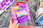 person holding a pack of poise pads over a cart