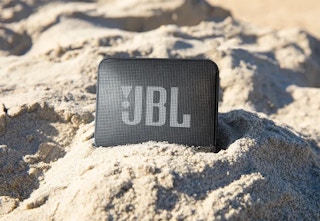 black JBL waterproof speaker in sand