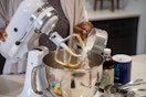 A person mixing cookie ingredients in a KitchenAid mixer