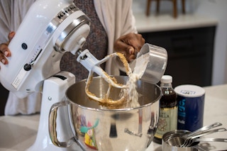 A person mixing cookie ingredients in a KitchenAid mixer
