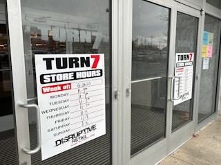 Turn7 store front entrance and hours sign posted on the window