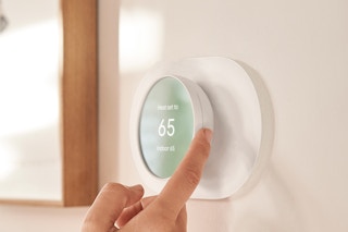 hand using a google nest thermostat