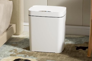 a small white trash can in a room on a rug