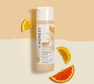 Shampoo bottle on a peach and creme background with orange slices